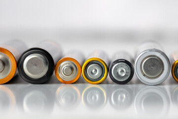 Batteries lie in a row on a white background, old used alkaline and saline batteries for single use