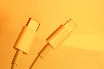 White Type-C cable and lightning, close-up on an orange background