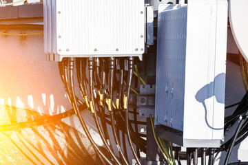 Close-up of a cellular antenna with many power cables, coaxial cables, optical fiber.
