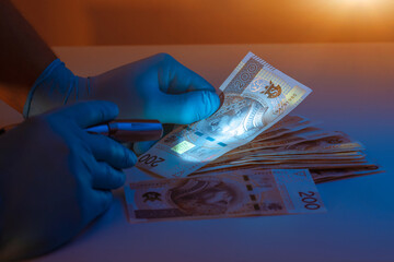 Checking counterfeit money with an ultraviolet lamp. Polish zloty - obrazy, fototapety, plakaty
