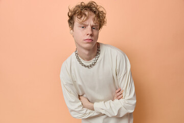 Horizontal shot of trendy cool confident ginger man He is wearing white shirt and chain frowning...