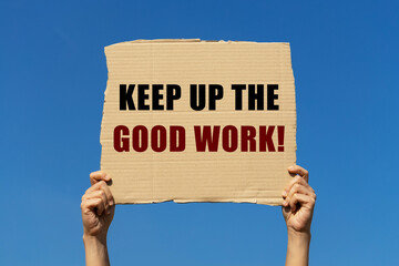 Keeo up the good work text on box paper held by 2 hands with isolated blue sky background. This...