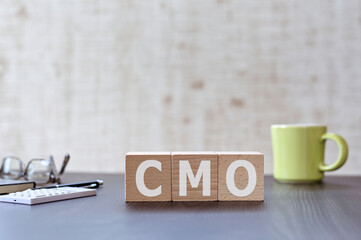 There is wood cube with the word CMO. It is an acronym for Chief Marketing Officer an eye-catching image.