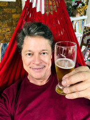 Relaxed handsome man drinking beer lying in a hammock.