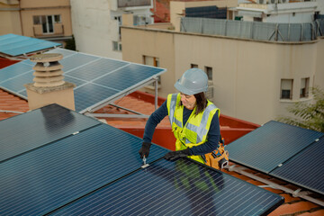 Female electrician engineer installing solar energy panels on city residential rooftop. Woman doing...