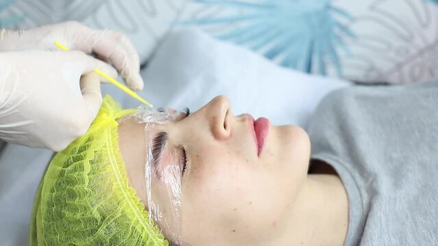 beautician in the process of laminating the eyebrows of a woman. Close-up of beautician's hands during eyebrow lamination