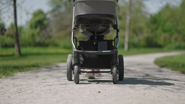 Slow motion - Shot of a lower part of a stroller being pushed on a sunny spring day
