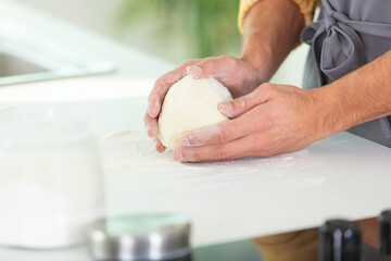 hands holding dough on floured work surface