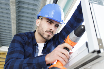 young handsome handyman using a drill at work