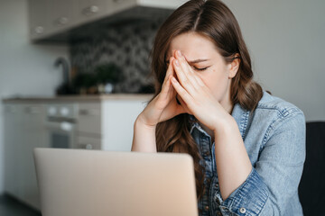 Female freelance with eyes closed is massaging head temples with suffering face expression. Tired...