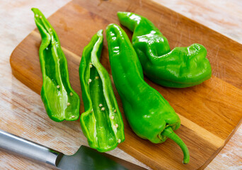 Fresh peppers on a wooden chopping board while cooking. Close-up image