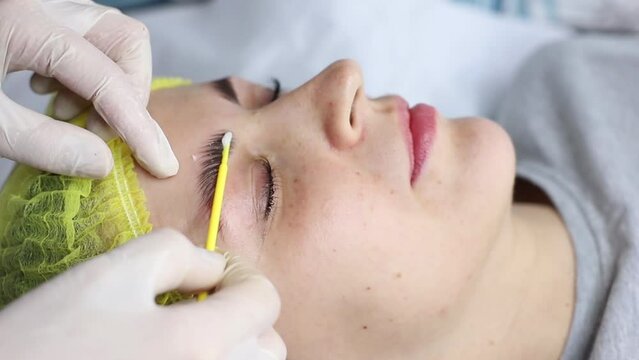 Close-up of beautician applying medical Botox on eyebrows after lamination