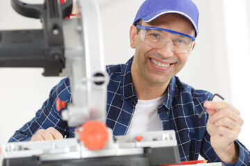 portrait of mature man by circular saw holding allen key