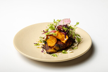 Fried fish with spices and vegetables, served on a plate with a white background.