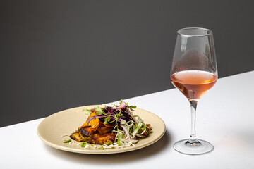 Fried fish with spices and vegetables accompanied by a glass of wine