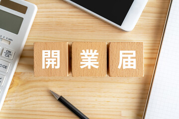 開業届と書かれたブロック、電卓、スマホ、ノート、ペン