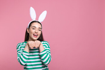 Happy woman wearing bunny ears headband on pink background, space for text. Easter celebration