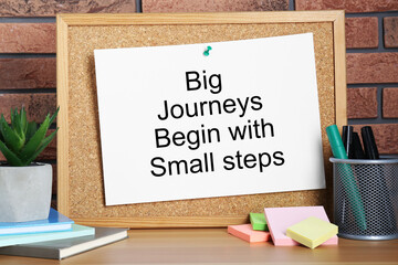 Corkboard and phrase Big Journeys Begin With Small Steps, houseplant, markers and books on table...