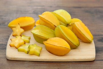 Cut and whole delicious ripe carambolas on wooden table