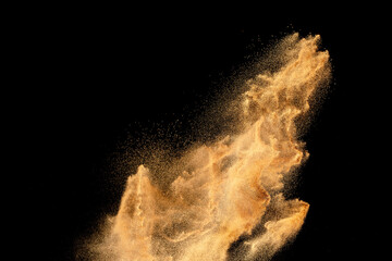 Brown sand explosion isolated on black background. Freeze motion of sandy dust splash.