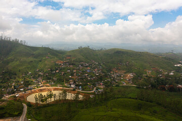 Fototapeta premium Top view of village among tea plantations. Houses of farmers growing tea. Tea estate landscape. Maskeliya.