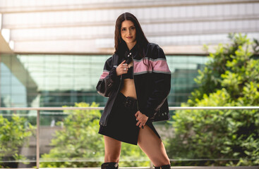 Urban chic: young brunette model wears leather jacket and long boots in public park with morning sunlight