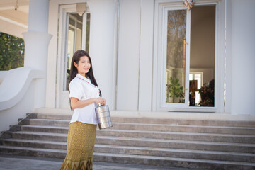 Beautiful thai woman in a white traditional thai dress is standing looking to the copy space while...