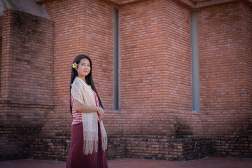 Beautiful thai woman in traditional thai dress standing and looking to to the camera with a smile.