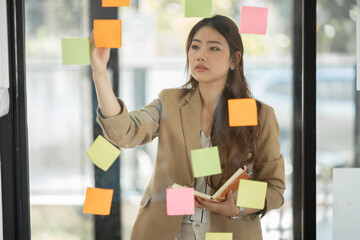 Two Asian businesswomen holding a note on the board, presenting about financial business.
