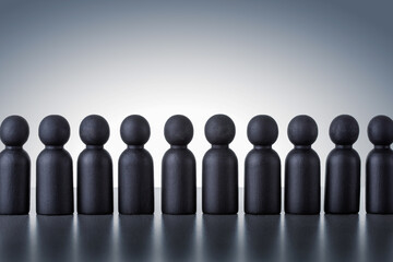 Concept of human resource. Many wooden human figures on grey background.