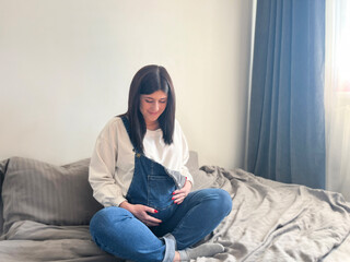 Waiting concept - happy woman at 9 months of pregnancy touching belly at home