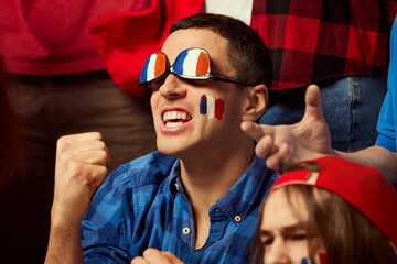 Football, soccer fans emotionally cheering up favourite france team. Man wearing glasses with...