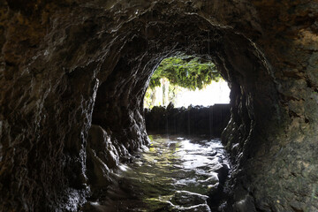 Inside the wet cave - trickles of water flow down from the stones at the entrance of the cave