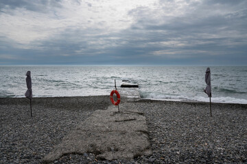 A deserted beach on the coast of Sochi and a lifebuoy on the pier against the background of a...