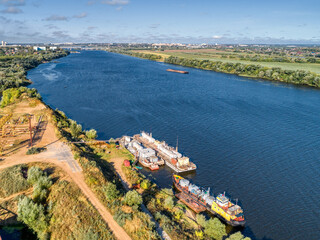 Small oil tankers stand at the river pier.