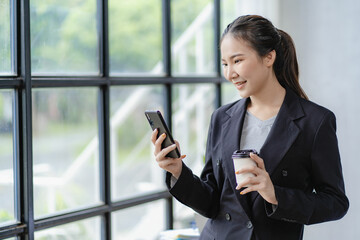 Serious asian businesswoman using laptop talking on phone consulting customer sitting at table sales manager focused business woman on mobile phone discussing work with customer by internet messaging