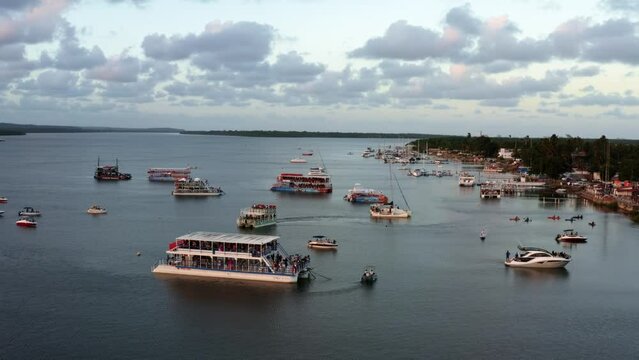 Dolly out aerial shot of the famous alligator beach, a river in Cabedelo, Paraiba, Brazil, near the coastal capital city of Joao Pessoa, with a group of tour boats watching the sunset