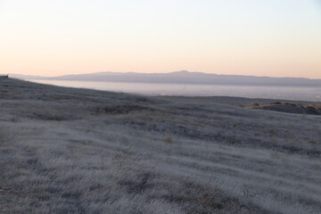 Beyond the golden grasses of summer lie views of Salinas valley and Monterey Bay in Central...