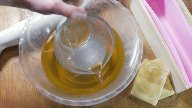 Pouring lye solution into oils for cold process soap production
