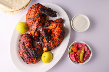 A plate of full thandoori chicken. Arabian spicy food tandoori whole chicken Bengaluru India . Platter served with salads. Al Faham Charcoal Grilled Chicken .