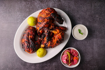 A plate of full thandoori chicken. Arabian spicy food tandoori whole chicken Bengaluru India . Platter served with salads. Al Faham Charcoal Grilled Chicken .