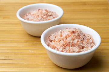 Two white bowls filled with coarse pink sea salt.