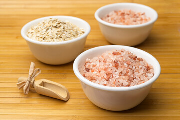White bowls filled with coarse pink salt and oats.