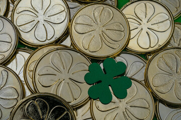 Golden coins with clovers background and a green clover made from paper. Decoration for St. Patrick's Day