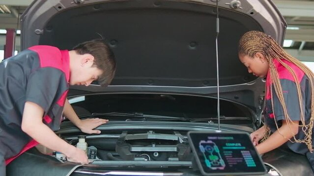 Two professional automotive mechanical partners check and repair an EV car battery and hybrid engine at a maintenance garage, expert electric vehicle service, and fixing occupations auto industry.
