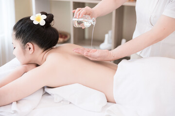 Young Asian woman getting Relaxing oil massage at beauty spa salon. Massage for health, Pour...