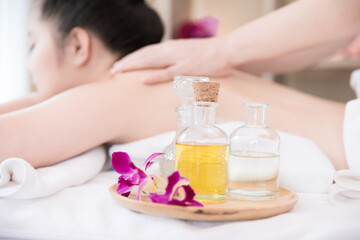 Obraz na płótnie Canvas Close up Essential Oil bottle and Young Asian woman getting Relaxing oil massage background at beauty spa salon. Massage for health