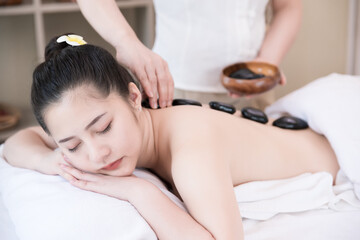 Fototapeta na wymiar Young Asian woman getting spa massage with hot stone massage at beauty spa salon. Relaxing massage for health