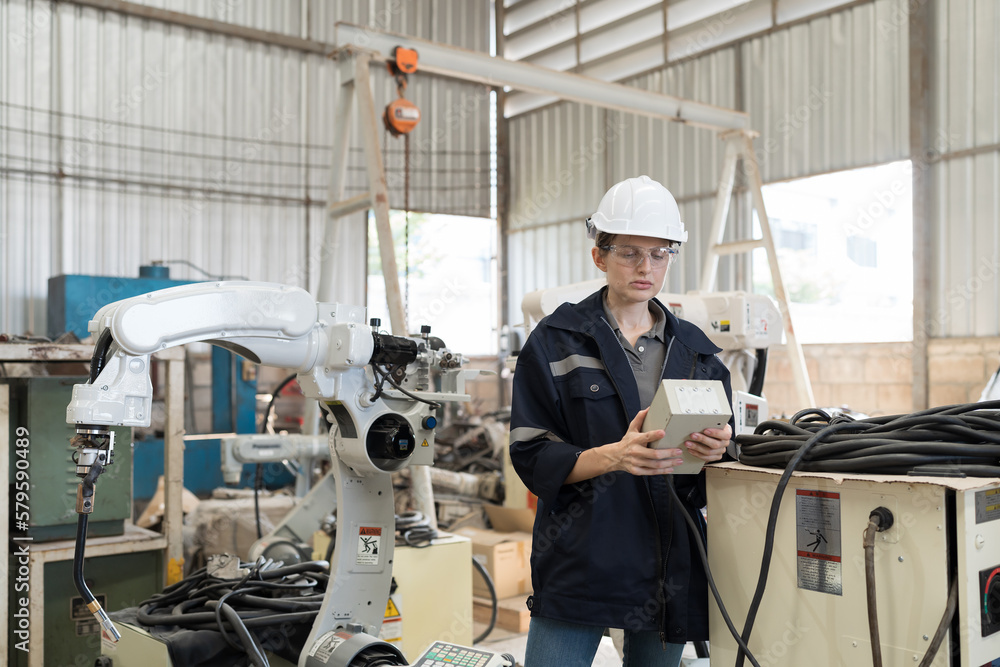 Fototapete female engineer control robot arm by remote robot control in workshop. woman technician working with