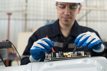 Male electrician worker checking, repair, maintenance operation electric system of robotic arm in factory. Male electrician using electrical meters working with operation electric system of robot arm